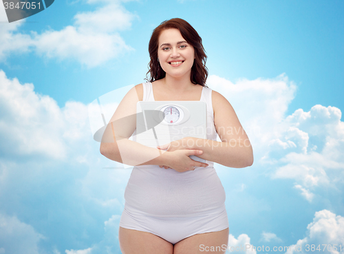 Image of happy young plus size woman holding scales