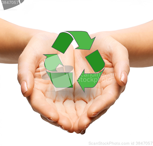 Image of close up of hands holding green recycling sign