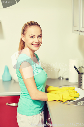 Image of happy woman washing dishes at home kitchen