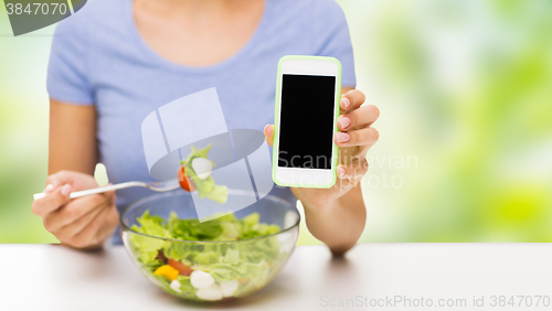 Image of close up of woman with smartphone eating salad