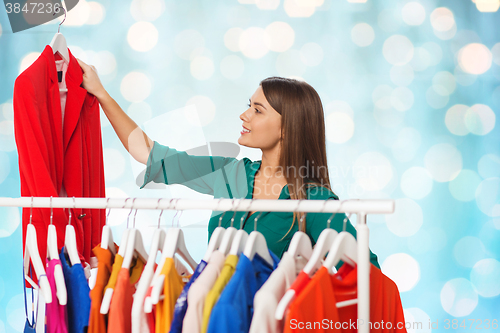 Image of happy woman choosing clothes at wardrobe