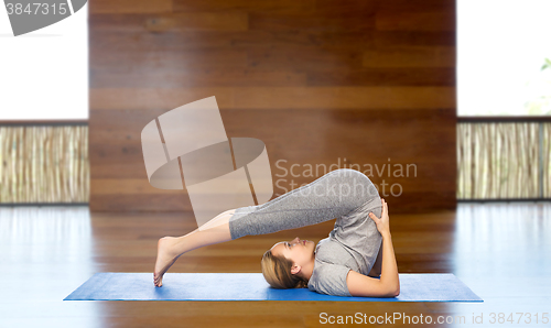 Image of woman making yoga in plow pose on mat