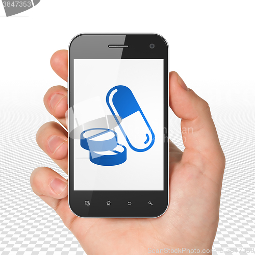 Image of Healthcare concept: Hand Holding Smartphone with Pills on display