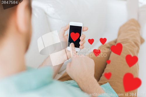 Image of close up of man sitting with smartphone at home