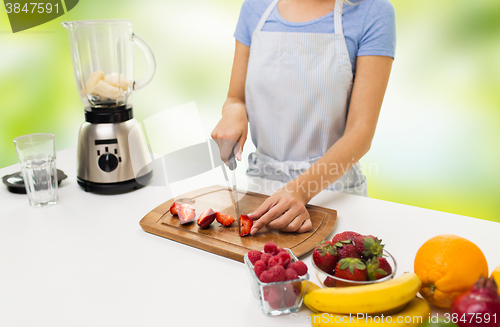 Image of close up of woman chopping strawberry at home
