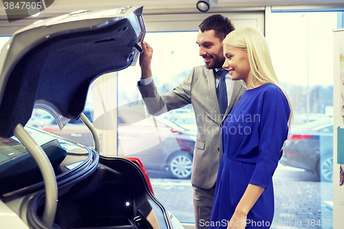 Image of happy couple with car dealer in auto show or salon