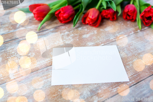 Image of close up of red tulips and blank paper or letter