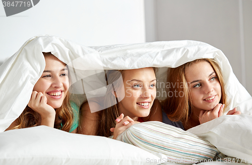 Image of happy young women in bed at home pajama party