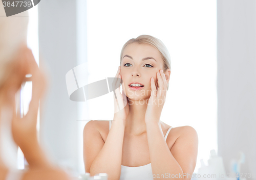 Image of happy young woman looking to mirror at bathroom