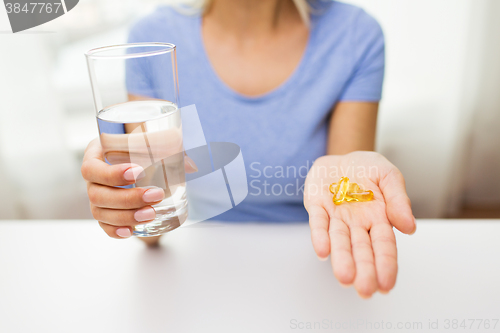 Image of close up of woman hands with capsules and water