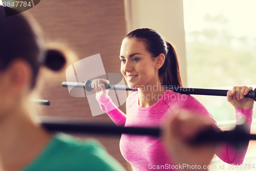 Image of group of people exercising with bars in gym