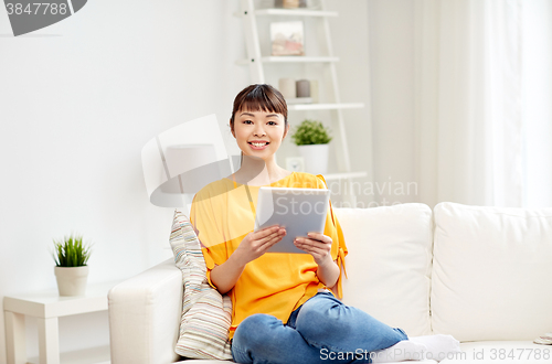 Image of happy young asian woman with tablet pc at home