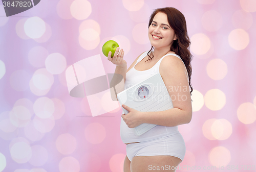 Image of happy young plus size woman holding scales