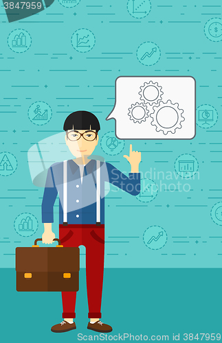 Image of Businessman pointing at cogwheels.