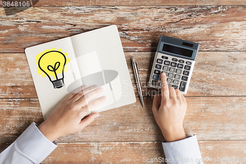 Image of close up of hands with calculator and notebook