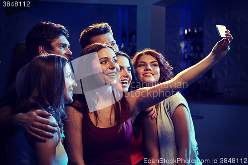 Image of friends with smartphone taking selfie in club