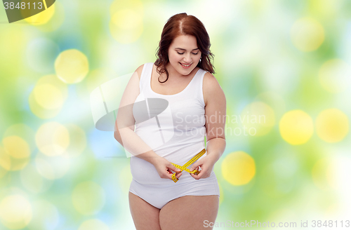 Image of happy young plus size woman with measuring tape