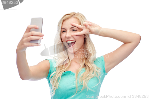 Image of smiling young woman taking selfie with smartphone