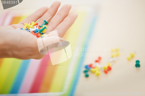 Image of Hand with colorful pushpins