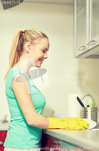 Image of happy woman washing dishes at home kitchen