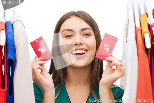 Image of happy woman with sale tags on clothes at wardrobe