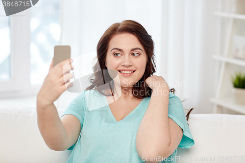 Image of happy plus size woman with smartphone at home