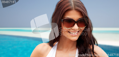 Image of smiling young woman with sunglasses on beach