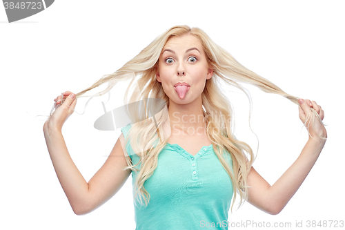 Image of happy young woman showing tongue and holding hair