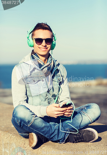 Image of happy young man in headphones with smartphone