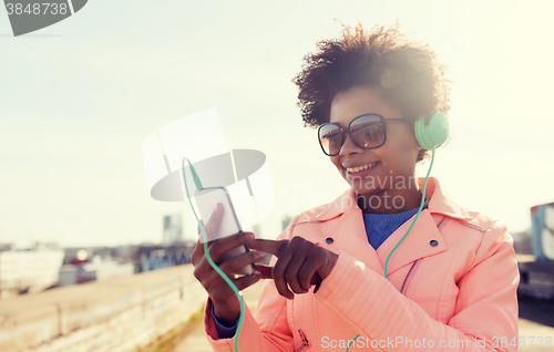 Image of happy young woman with smartphone and headphones