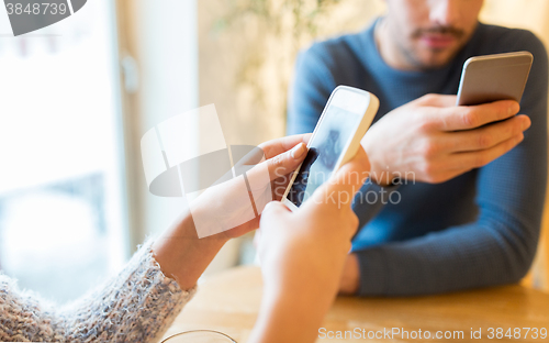 Image of close up of couple with smartphones at cafe