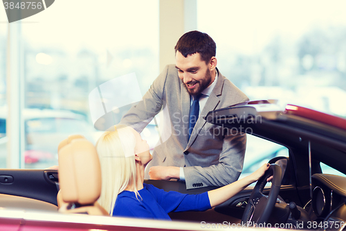 Image of happy couple buying car in auto show or salon