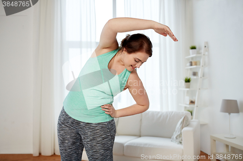 Image of plus size woman exercising and stretching at home