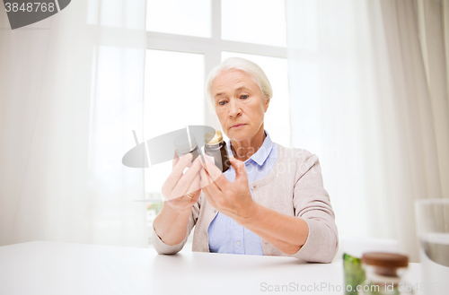 Image of senior woman with medicine jars at home