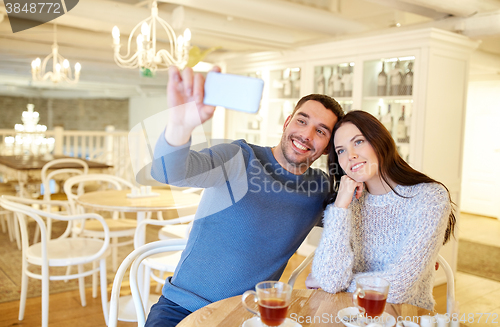 Image of couple taking smartphone selfie at cafe restaurant