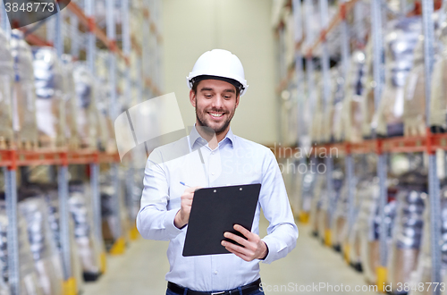 Image of happy businessman with clipboard at warehouse