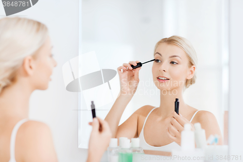 Image of woman with mascara applying make up at bathroom