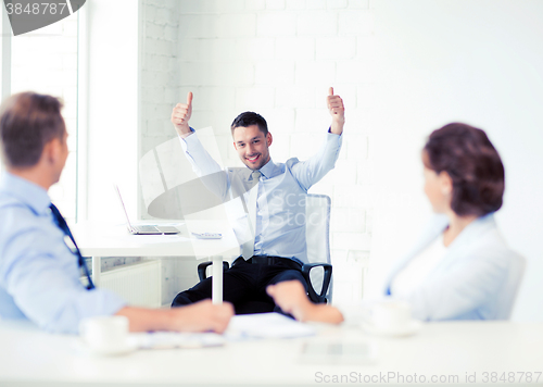 Image of happy businessman showing thumbs up in office