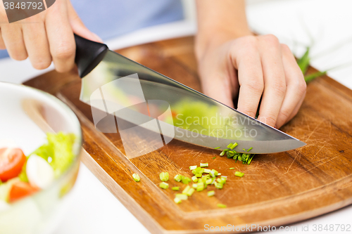 Image of close up of woman chopping green onion with knife