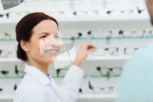 Image of optician showing glasses to man at optics store