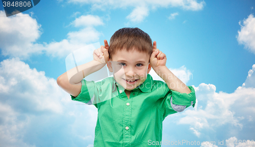 Image of happy little boy having fun and making horns