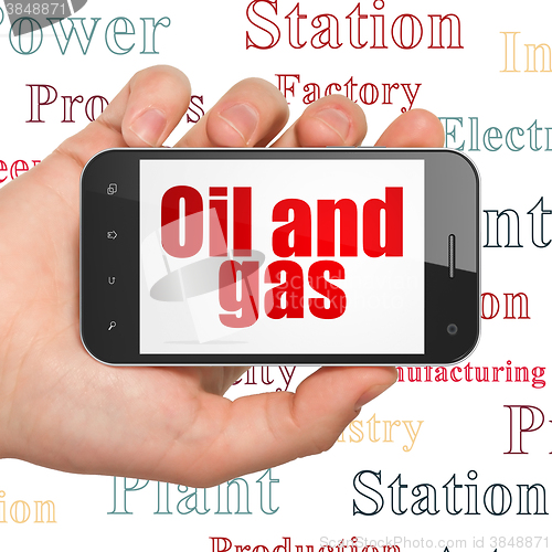 Image of Industry concept: Hand Holding Smartphone with Oil and Gas on display