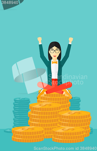Image of  Happy business woman sitting on coins.