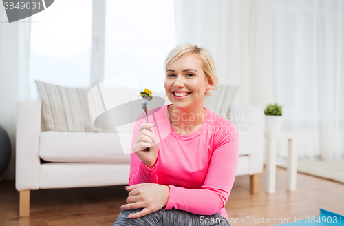 Image of smiling young woman eating salad at home
