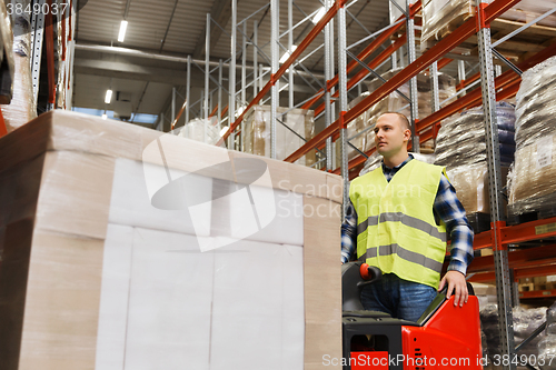 Image of man with tablet pc operating forklift at warehouse