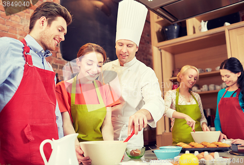 Image of happy friends and chef cook baking in kitchen