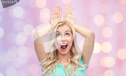 Image of happy smiling young woman making bunny ears