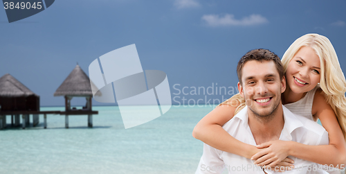 Image of happy couple having fun over beach with bungalow
