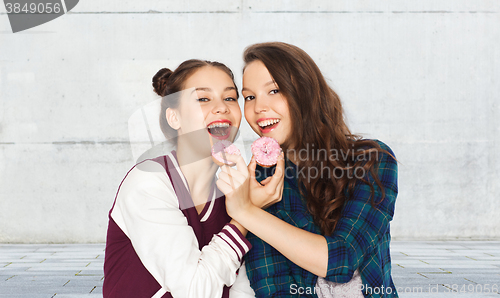 Image of happy pretty teenage girls eating donuts