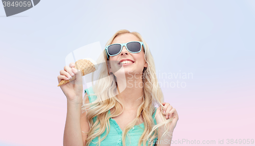 Image of happy young woman in sunglasses eating ice cream